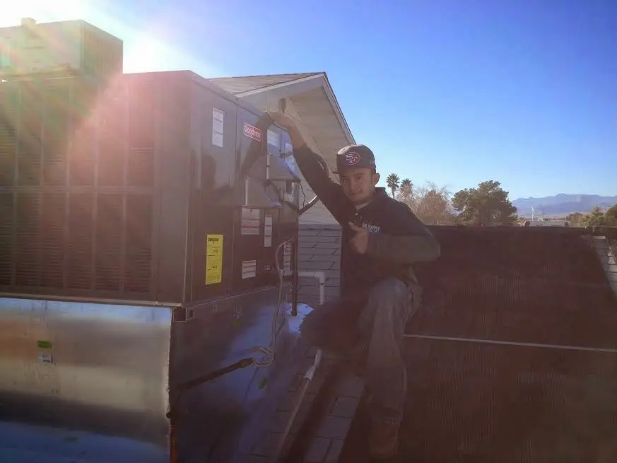 HVAC technician performing Air Duct Cleaning on a rooftop unit in Gaines